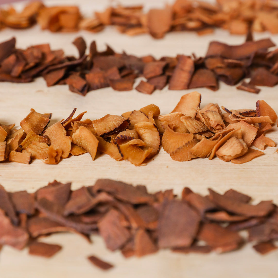 Fileiras horizontais de chips de coco nos sabores cacau, tradicional, café e gengibre dispostos lado a lado.